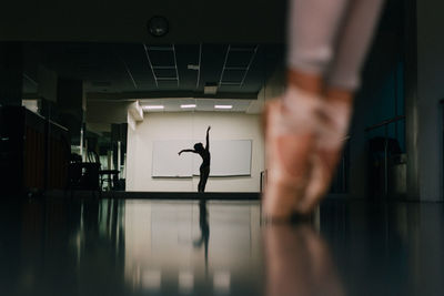 Low section of woman practicing ballet with reflection in mirror at dance studio