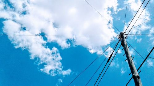 Low angle view of electricity pylon against blue sky