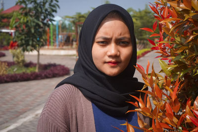 Portrait of beautiful young woman standing by plants during autumn