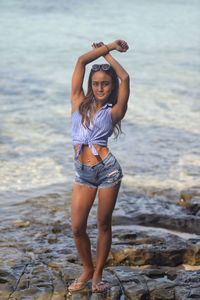 Full length portrait of young woman standing on beach