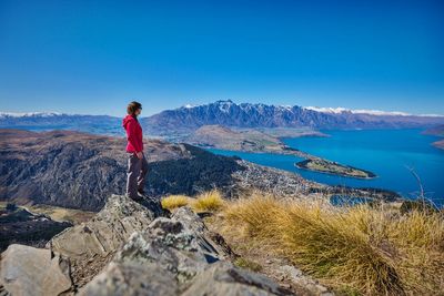 Man standing on mountain against blue sky