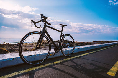 Bicycle by road against sky