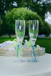 Close-up of wine glasses on table against trees