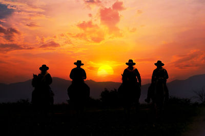 Silhouette people against orange sky