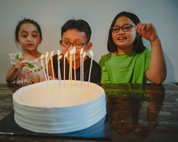 Children celebrating birthdays together. colourful candles on white cake.