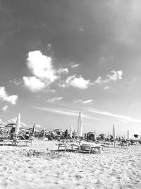 Closed canopies with sun loungers on beach against the sky