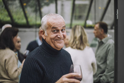 Portrait of happy mature man wearing sweater at dinner party