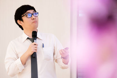 Full length of man wearing eyeglasses standing against wall