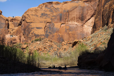 People paddle packrafts below high cliffs on escalante river, utah