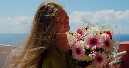 Woman sniffs bouquet of flowers outdoors. happy girl smiles. 