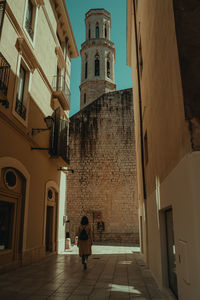 People walking in alley amidst buildings in city