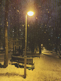 Empty bench in park during winter at night