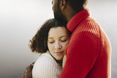 Young woman with eyes closed embracing boyfriend