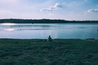 Rear view of person relaxing by lake