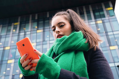 Beautiful woman using smart phone in front of building