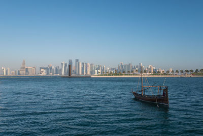 Scenic view of sea by buildings against clear blue sky