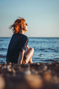 Woman enjoying at beach against sky