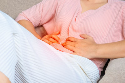 Midsection of woman lying on bed at home