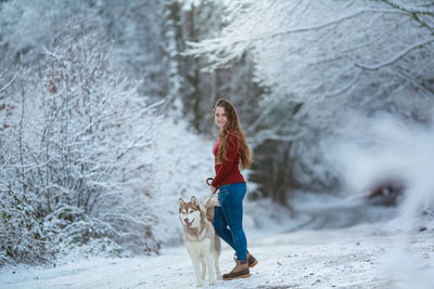 Full length of woman with dog on snow