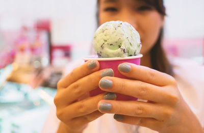 Midsection of woman holding ice cream in parlor 