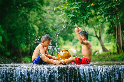 Full length of shirtless boy splashing water in tree