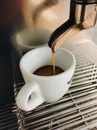 Close-up of coffee dripping down into espresso cup