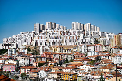 Buildings in city against clear blue sky