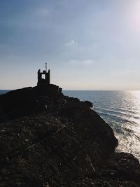 Lighthouse by sea against sky