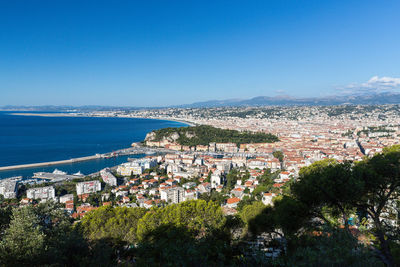 Aerial view of townscape by sea against clear blue sky