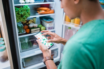 Midsection of woman using mobile phone in store