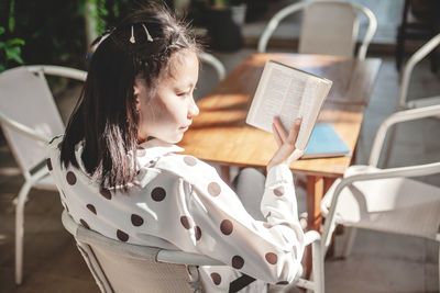 Girl looking away while sitting on chair