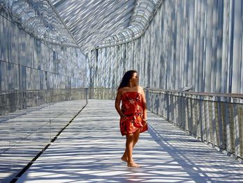 Rear view of woman with umbrella walking on walkway