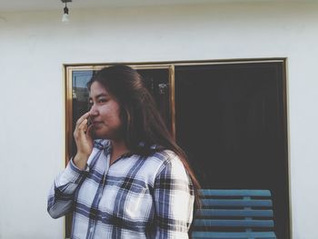 Portrait of senior woman standing against wall at home