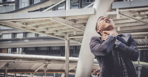 Businessman choking neck outside office building