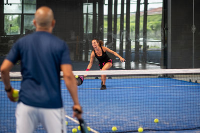 Monitor teaching padel class to woman, his student - trainer teaches young girl how to play padel
