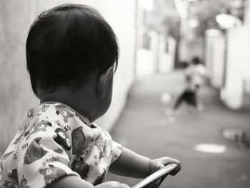 Close-up of toddler on chair looking at street in town