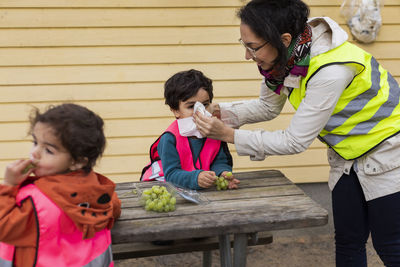 Preschool teacher and students eating grapes outdoors