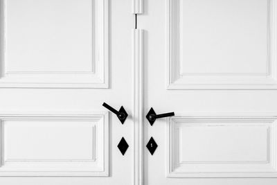Full frame shot of closed white door with black handle