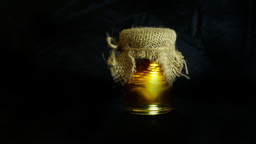Close-up of illuminated lamp on table against black background