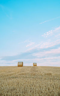 Hay bales on field against sky