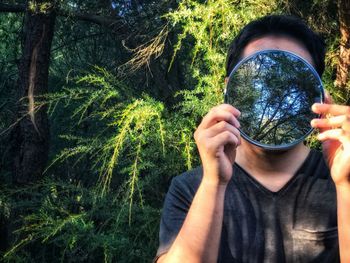 Portrait of man holding plant in forest