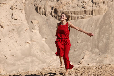 Full length of a smiling young woman standing on land