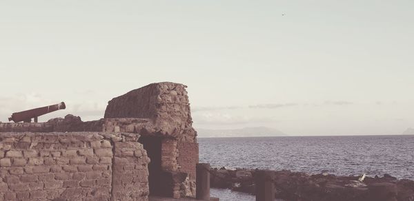 Stone wall by sea against sky