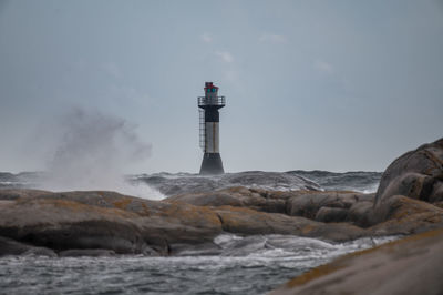 Lighthouse by sea against sky