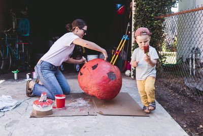 Mother painting halloween costume by son