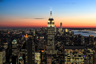 Illuminated new york cityscape against sky at sunset