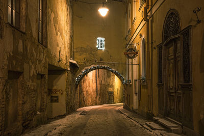 Empty alley amidst buildings in city at night