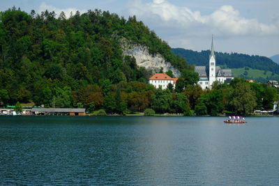 Scenic view of river by buildings against sky