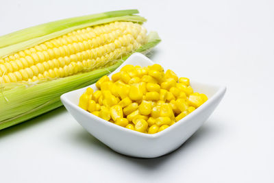 Close-up of yellow and vegetables on table against white background