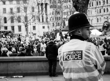 Rear view of police officer wearing reflective clothing in city